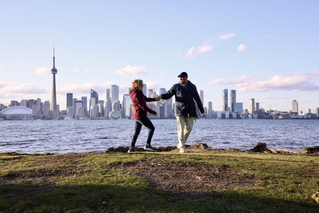 Ali and Jas explore shores of Lake Ontario with Toronto skyline in the background during a spring trip to see the cherry blossoms.