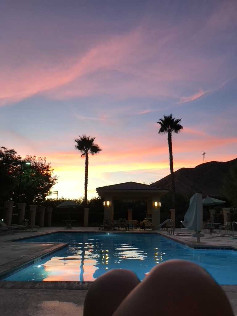 Candy colored sky as sun sets on the pool and palm trees of a hotel in California