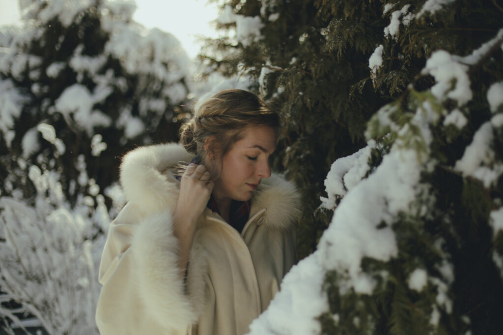 Alison stands along a snow covered hedge.