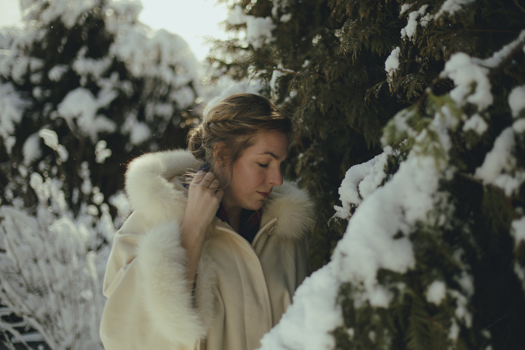 Ali stands amongst greenery covered in freshly fallen snow.