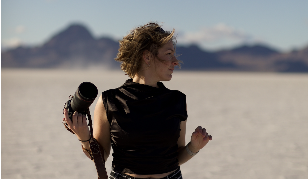 Ali standing on salt flats with her camera in hand