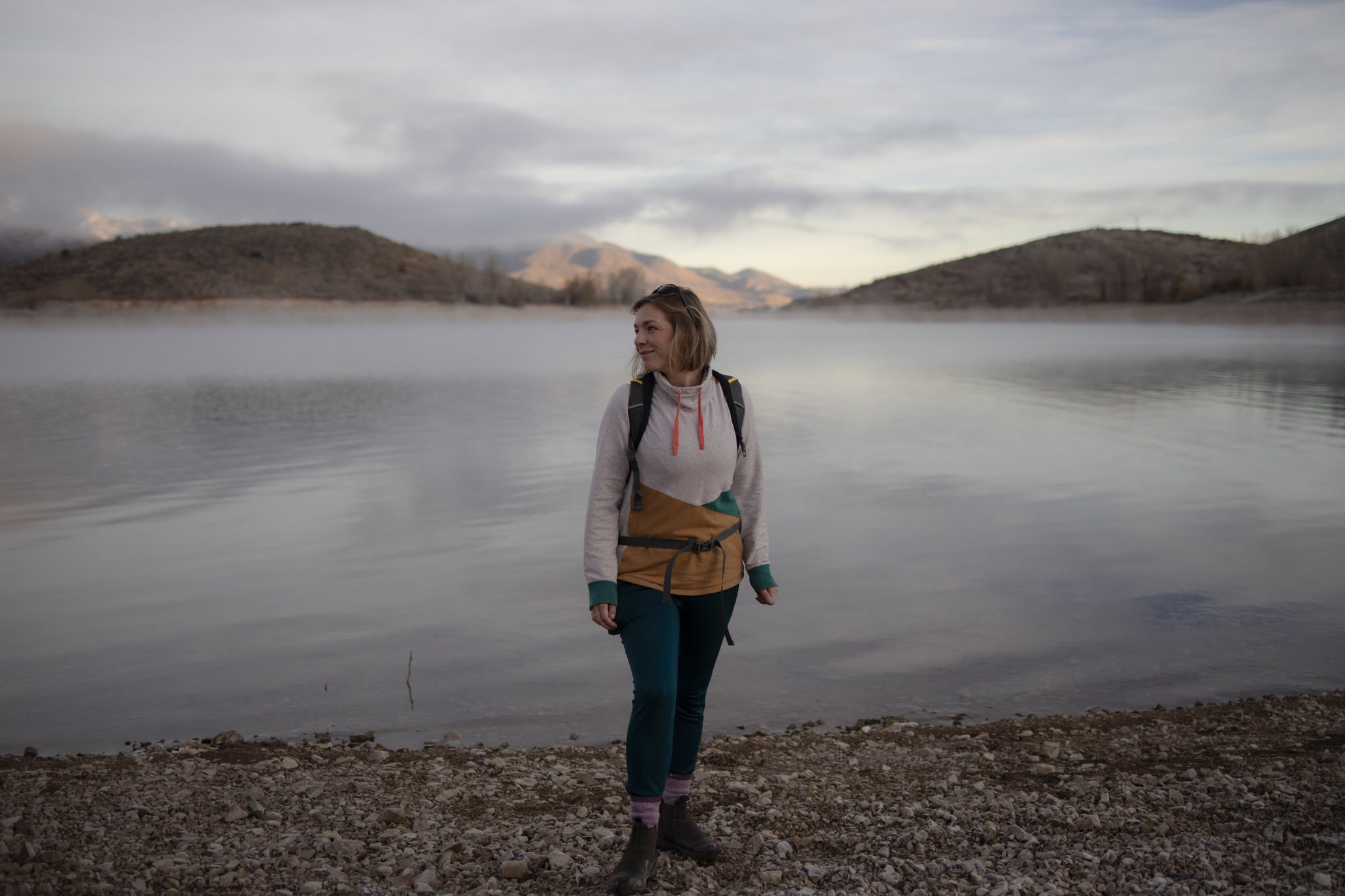 Alison stands on the shore with mountains in the background.
